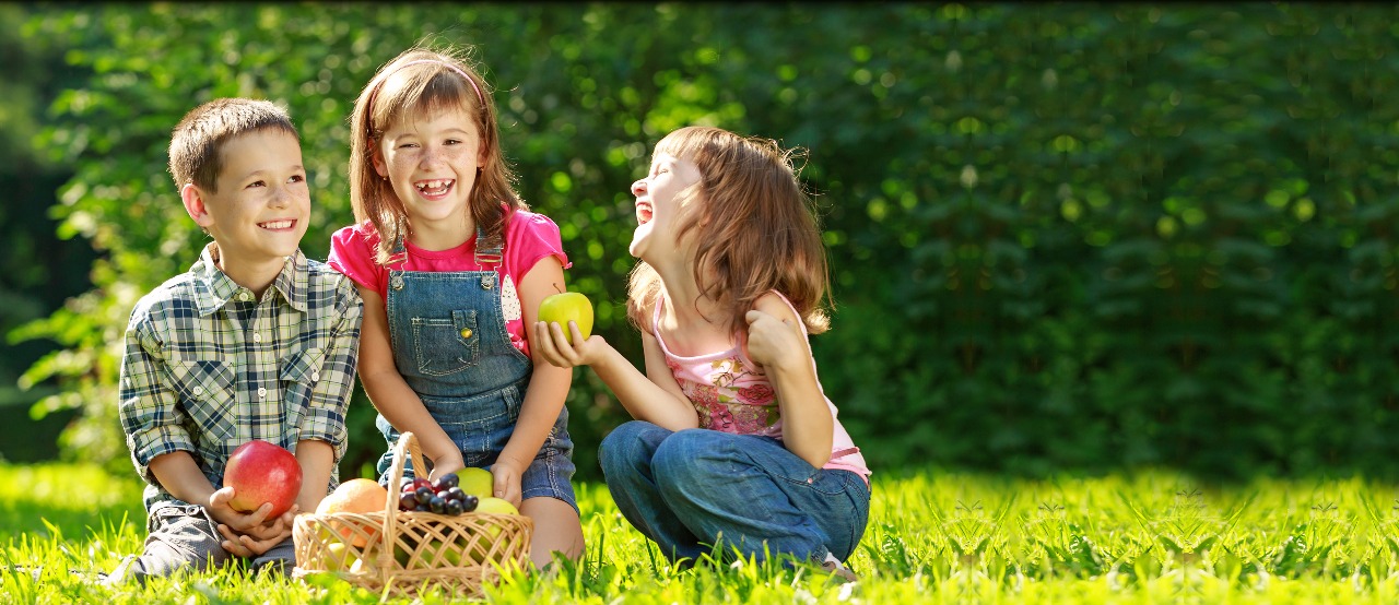 niños felices compartiendo frutas en un jardín